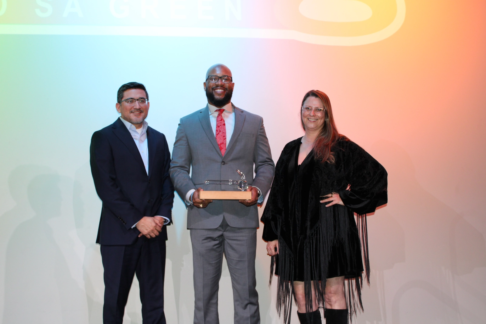 three people stand with an award